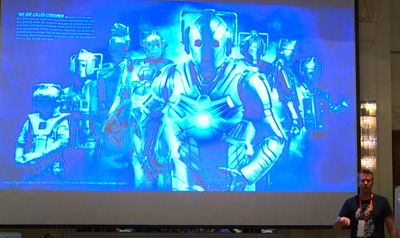 Speaking at an event with me on stage and a screen behind me.